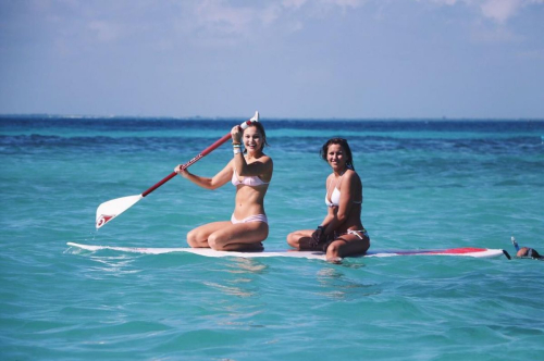 Olivia Holt paddleboarding in bikini on blue ocean with friend, summer vacation scene