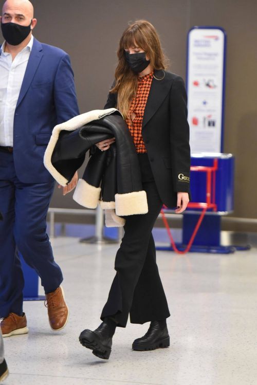 Dakota Johnson in Checked Shirt With Gucci Suits at JFK Airport in New York