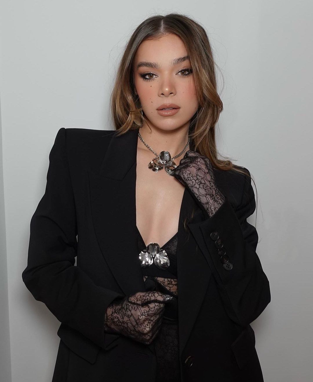 Bumblebee actress Hailee Steinfeld celebrity photoshoot wearing crossbody minidress, black blazer, silver necklace and net hand gloves