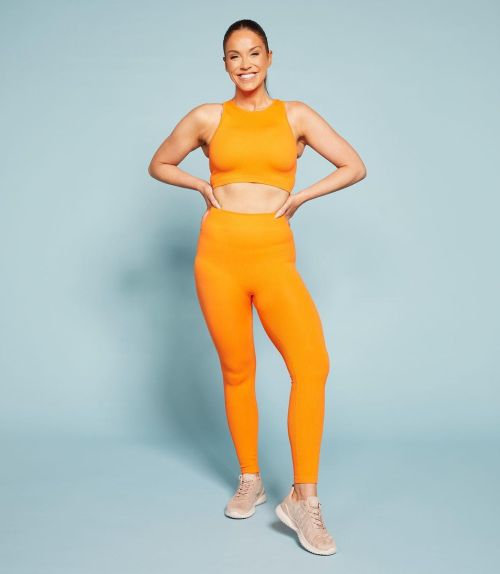 Author Vicky Pattison Fashion photoshoot in orange blouse and sweats with skin color sports shoes