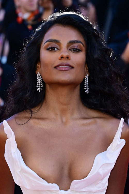 Simone Ashley posing confidently on the Cannes red carpet in a white Vivienne Westwood ball gown