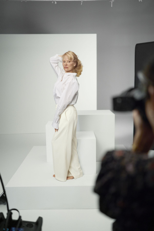 Profile view of Pamela Anderson on white set during Biolage campaign filming wearing minimalist sustainable fashion